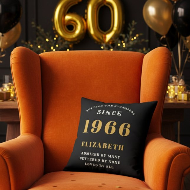 60-årspresent Personlig 1966 Svart Guld Kudde (A personalized black pillow on a vibrant orange velvet wingback armchair )