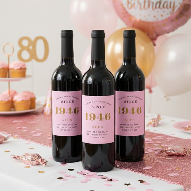 80:e födelsedag Namn 1946 Rosa Guld Elegant Chic Vinflaska Etikett (1946 Pink wine bottle labels on a party table.)