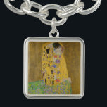 Älskare Kissing Embrace av Gustav Klimt Armband<br><div class="desc">Solljus blundar från det virvlande guldomfamning som omger älskare i Gustav Klimts mästerverk, The Kiss. Scenen är en paradox med intimitet och isolering. Paret står på en avgrund, en fält av färgstarka blommor på fötterna, men ändå är de omedvetna mot omvärlden. Deras blickar är låsta, deras kroppar är sammanflätade i...</div>