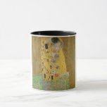 Älskare Kissing Embrace av Gustav Klimt Mugg<br><div class="desc">Solljus blundar från det virvlande guldomfamning som omger älskare i Gustav Klimts mästerverk, The Kiss. Scenen är en paradox med intimitet och isolering. Paret står på en avgrund, en fält av färgstarka blommor på fötterna, men ändå är de omedvetna mot omvärlden. Deras blickar är låsta, deras kroppar är sammanflätade i...</div>