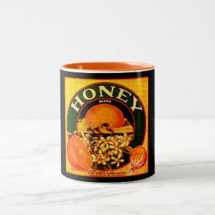 Annonsetikett för orange av honungsfrukt i vintage Två-Tonad mugg