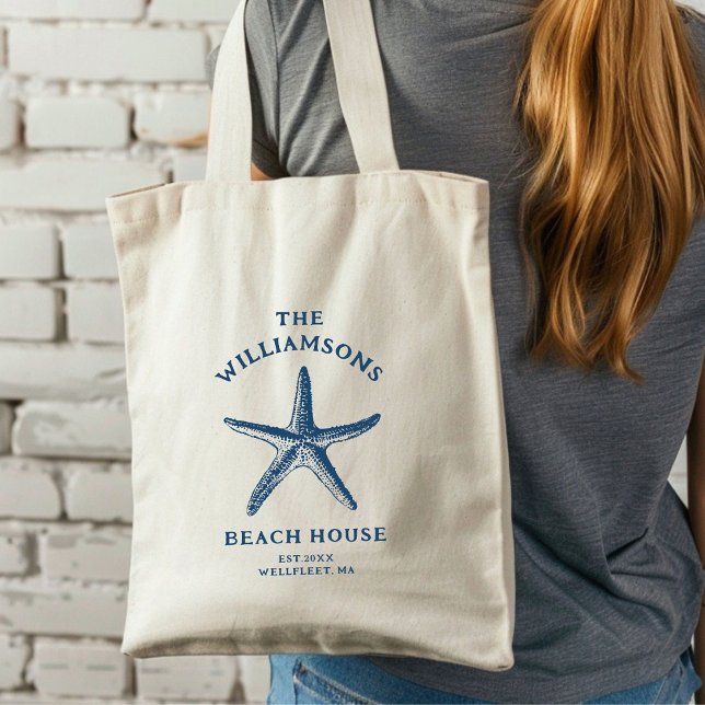 Anpassningsbar Blue Coastal Starfish Beach House Tygkasse (A woman with long hair carries a cream tote bag featuring a blue starfish design.)