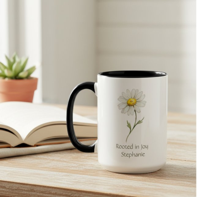 April födelsedagsblomma Tusenskönast vattenfärg Mugg (A "Rooted in Joy" daisy mug sits on a wooden table, a perfect thoughtful gift for her birthday.)