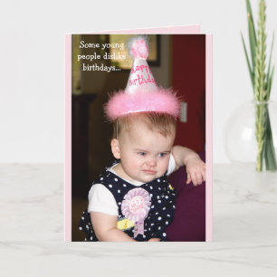 Baby tittar grumpy på henne första födelsedagsfest kort