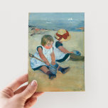 Barn i Beach | Mary Cassatt vykort<br><div class="desc">Barnen på stranden (1884) av Mary Cassatt fångar ett ömtåligt ögonblick av två barn som leker vid havet. Målningen har mjuk, muterad färg och milda penseldrag som återspeglar barndomens skonsamma oskuld. Kassatts imponerande stil tar med sig den lugnande strandinställningen och barns interaktion till livet med subtil charm. Använda verktygen för...</div>