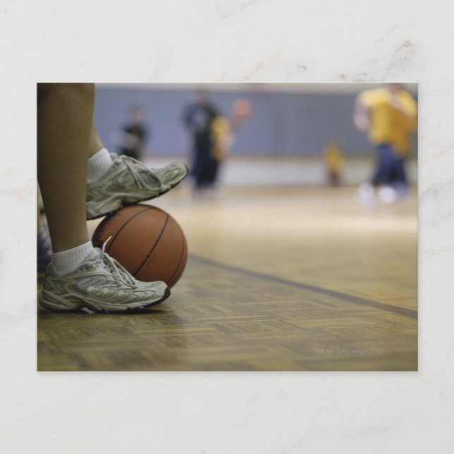 Basketbollspelare som håller boll med fötterna vykort (Framsida)