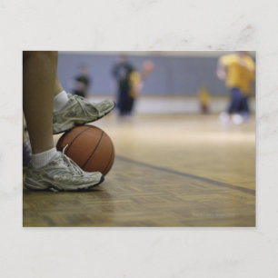 Basketbollspelare som håller boll med fötterna vykort