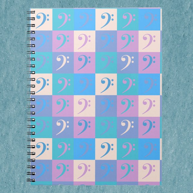 Bassklavmönster Pastell Anteckningsbok (A notebook with a pattern of bass clef music symbols in blue, yellow, pink and purple.)