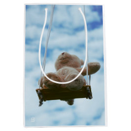 Beertje op schommel met bewolkte blauwe lucht.