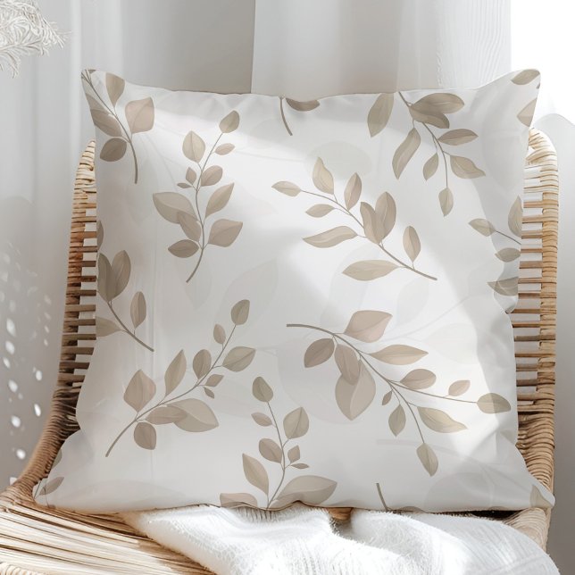 Beige och vita akvarellblad kudde (Beige and White Watercolor Leaves Throw Pillow in a sunny rattan armchair.)
