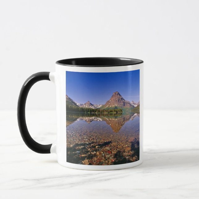 Berg reflekteras i lugna Two Medicine Lake i Mugg (Vänster)