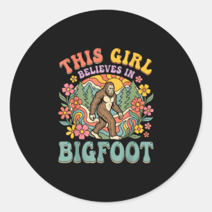 Bigfoot-flicka tror skog blommig solnedgång runt klistermärke