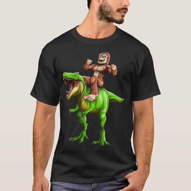 Bigfoot Sasquatch Riding Dinosaur Funny T-Rex T Shirt (Framsida)