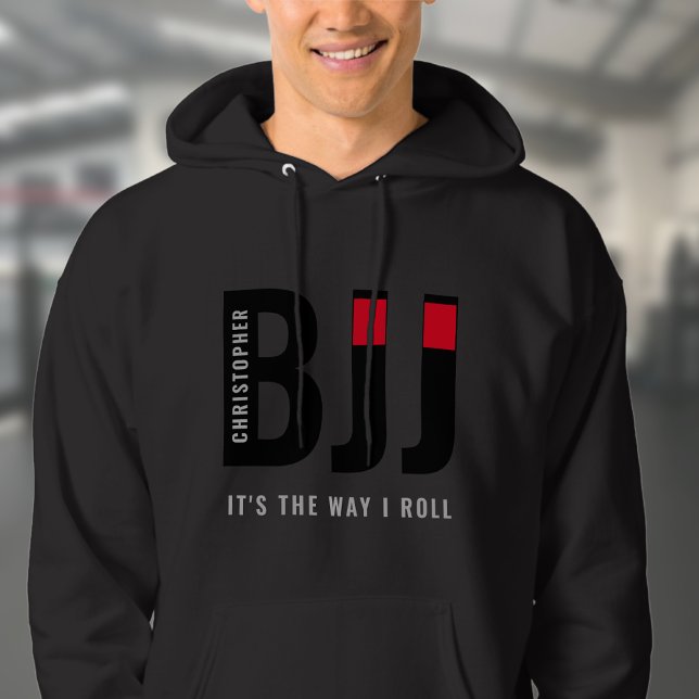 BJJ Brasilian Jiu Jitsu Add Namn Black Bälte Hoodie (Unisex black BJJ hoodie worn by male model in a gym.)