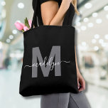 Black Trendy Modern Script Name Monogram Tygkasse<br><div class="desc">Personalized Elegant Black Trendy Modern Script Name Monogram Tote Bag. Add a touch of sophistication to your everyday style with this chic tote bag. Featuring a sleek gray initial centered on a crisp black background, with a clean and modern design on both sides, this tote combines elegance with practicality. Perfect...</div>