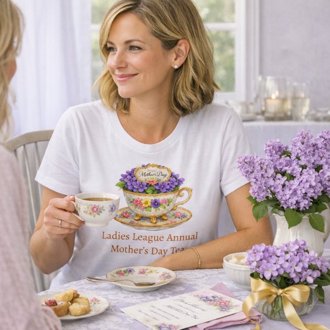 Blomsterliknande Tekopp Morsdags Teevenemang T Shirt (A woman sits at a tea table wearing a white “Ladies League Annual Mother’s Day Tea” T‑shirt )