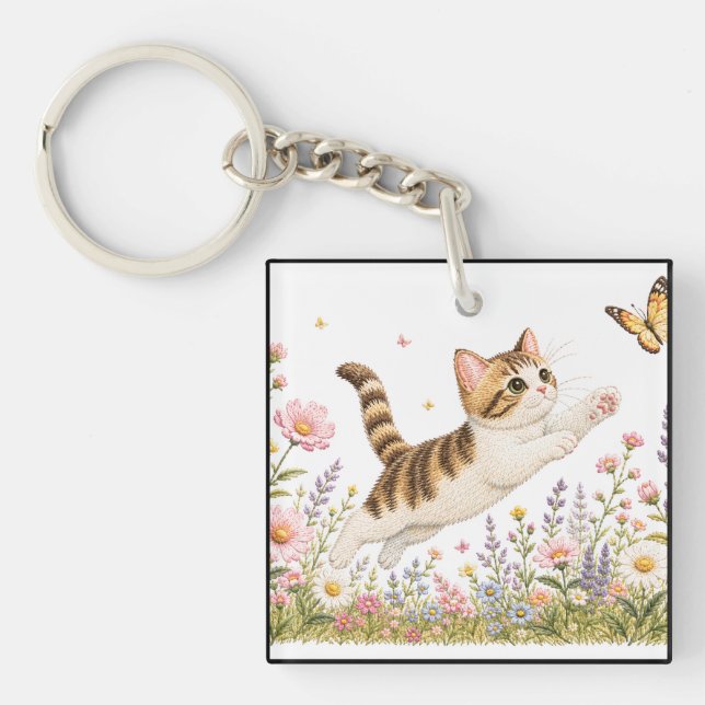 Broderad kattunge jagar fjäril i vildblomma (Framsidan)