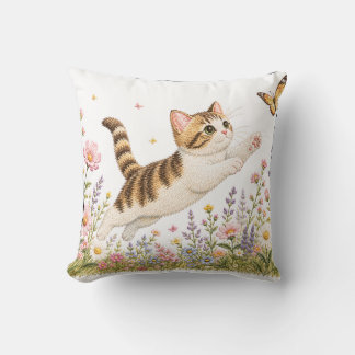 Broderad kattunge jagar fjäril i vildblomma kudde