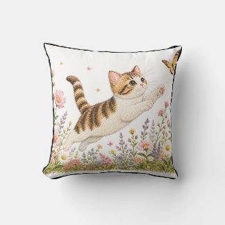 Broderad kattunge jagar fjäril i vildblomma kudde
