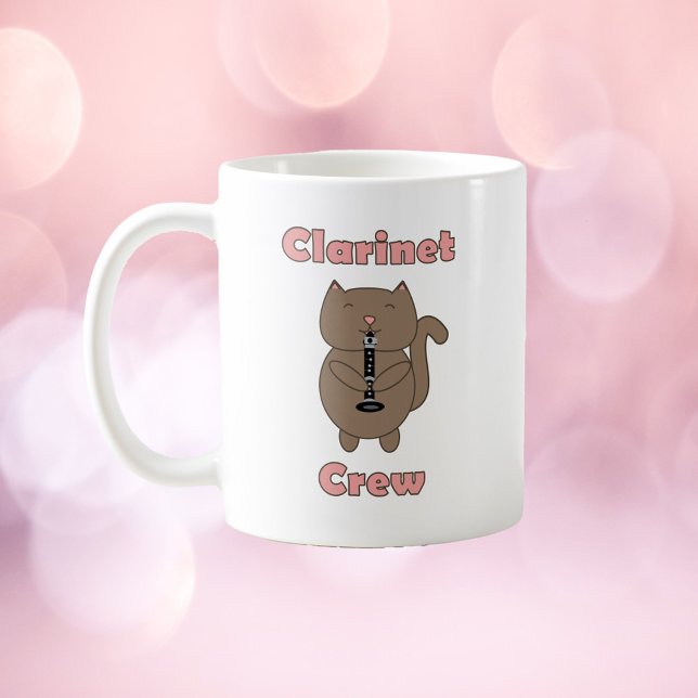 Clarinet Crew Cat Brown Rosa Kaffemugg (A mug with a brown cat playing the clarinet and the words clarinet crew in pink.)