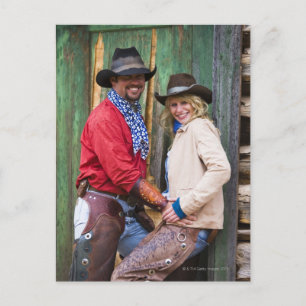 Cowboy and cowgirl holding hands in front of an vykort