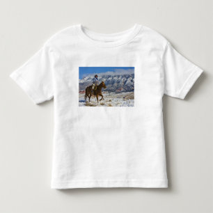 Cowboy till häst iklädd läderchapsar tee