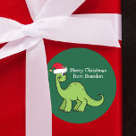 Cute Juldinosaur i Santa Hat Anpassningsbar Kids Runt Klistermärke<br><div class="desc">Fantastisk grönt leker och tittar mycket söt i en helgdag röd julhatt. Barn kommer att kärlek den här coola grönt julfest-märkningen. Anpassa den här julklappen med din egen text i vitt.</div>