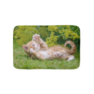 Cute lustig kattunge som leker i en blomsterträdgå badrumsmatta
