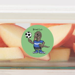 Cute roligt Komodo draon spelar fotboll tecknad Klistermärke