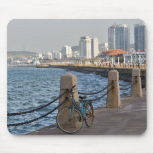 Cykel vid strandpromenaden med Yantai stads siluet Musmatta