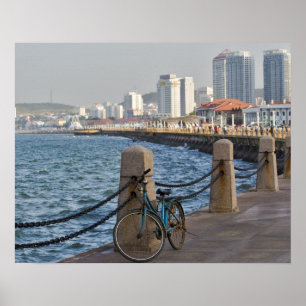 Cykel vid strandpromenaden med Yantai stads siluet Poster