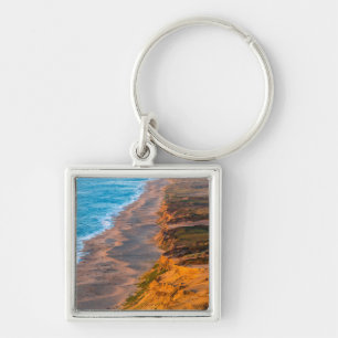 Dagens sista ljus träffar den sandiga stranden vid fyrkantig silverfärgad nyckelring