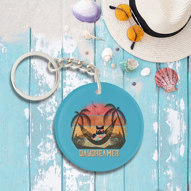 Daydreaming Coola Kats tropiska rymdrad (A Daydreaming Cool Cat's Tropical Escape Round Keychain on the table.)