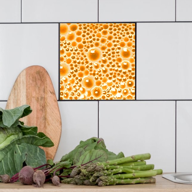 Dekorativ platta med bubblor, orange marmelad kakelplatta (Orange marmalade bubble tile shown  in a kitchen.)