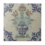 Delft Tile Antique Ceramic Flower Pot Kakelplatta<br><div class="desc">Ta med dig ditt utrymme med den här vintagens pompadour-platta som är så charmerande att den är enkel och har en snygg, flerfärgad blomkruka. Denna ursprungliga bild av den offentliga domänen från Rijksmuseum visar den historiska nederländska DelSoftware karakteristiska konst. Den centrala blomkrukan, med blått, grönt och orange blomning, är kantad...</div>