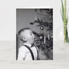 Den lilla pojken blåser ut ljus på Julgran Helgkort