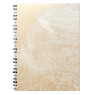 Den pastellfärgade det strandfotografisanden och anteckningsbok med spiral