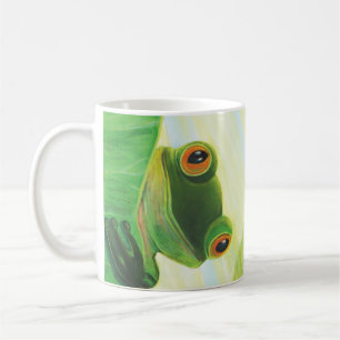 Den storögda gröntens groda bakom den lila plattan kaffemugg