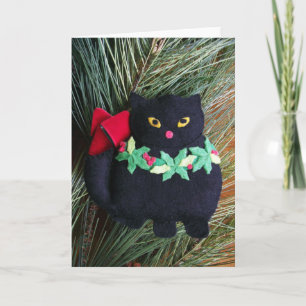 Den svart katten klädde med filt julprydnaden, helgkort