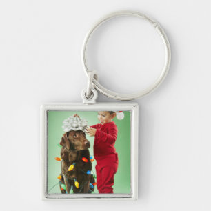 Den unga pojken som slår in jul, tänder runt om en fyrkantig silverfärgad nyckelring