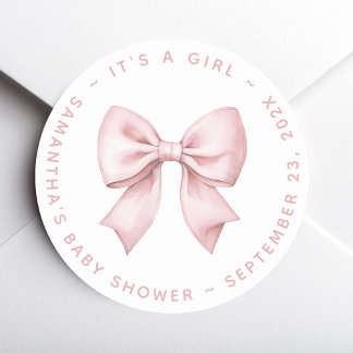 Det är en baby shower för en tjej med rosa rosett runt klistermärke