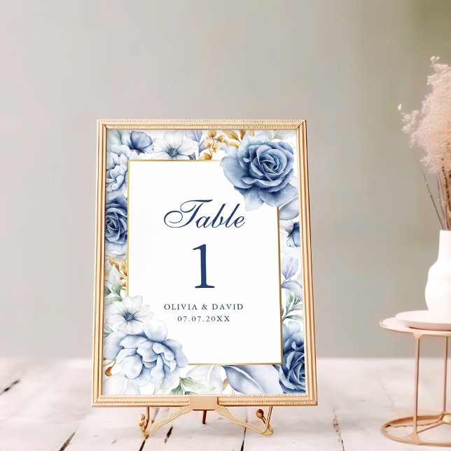 Det moderna Bordsnumret Bröllop vid Blommigten vid (Modern Blue and Gold Floral Wedding Table Number on a rustic white wooden table next to flowers)