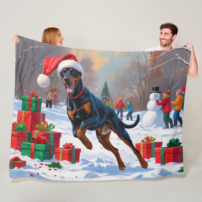 Dobermann springer i snö med julhatt fleecefilt (På plats)