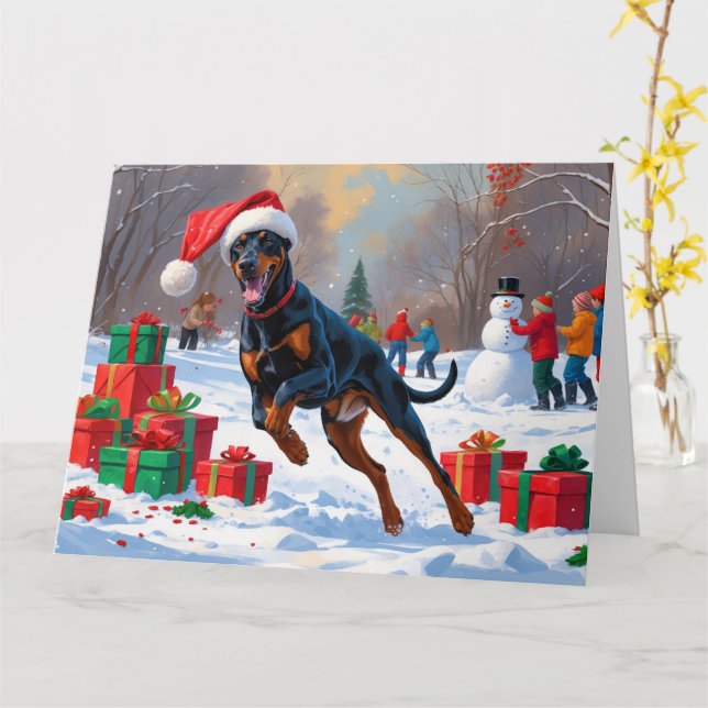Dobermann springer i snö med julhatt kort (Gul blomma)