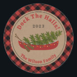 Docka Halls Canoe Julgran Play Runt Klistermärke<br><div class="desc">Illustration av en röd kanot som dekoreras med julen ljus med Julgran inuti. Bakgrunden är brunkardstock med röd och svart buffel plaid gräns. Anpassa texten.</div>