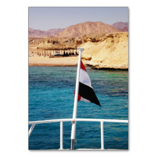 Egyptisk flagga mot bakgrund av azure vatten bordsnummer