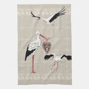 Elegant varm beige folkdräkt stork 2026 kalender kökshandduk
