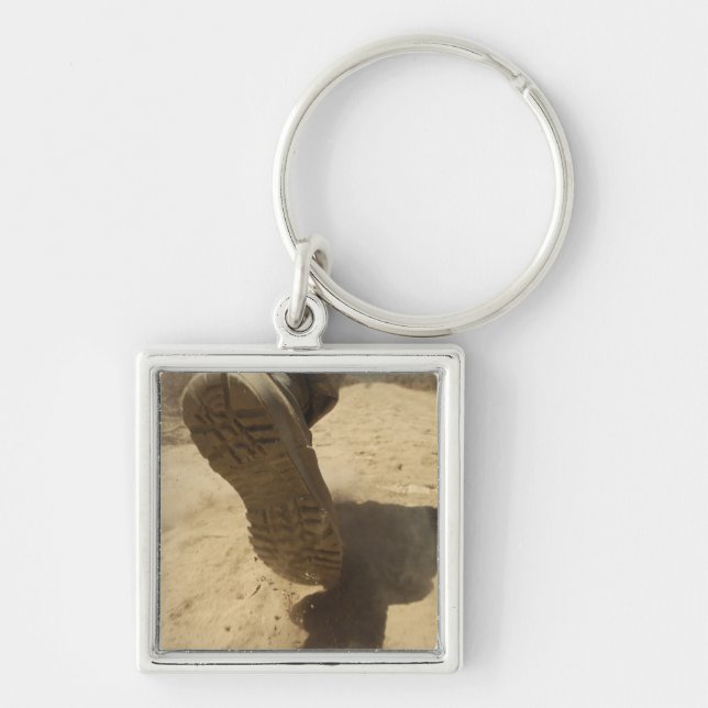 En amerikansk soldat går längs en smutsig väg fyrkantig silverfärgad nyckelring (Framsidan)