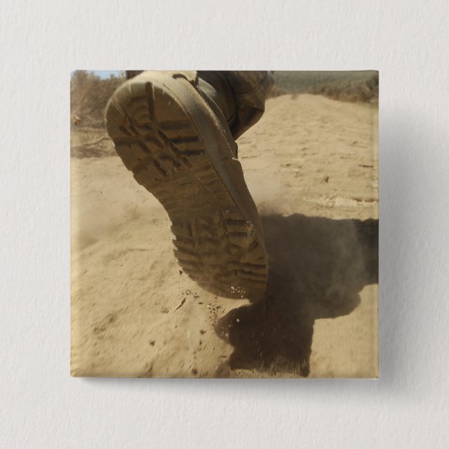 En amerikansk soldat går längs en smutsig väg knapp (Framsida)