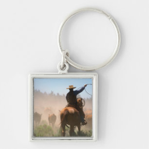 En cowboy som arbetar med hjorden på en boskap fyrkantig silverfärgad nyckelring